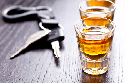 A couple of glasses filled with liquid next to some car keys.