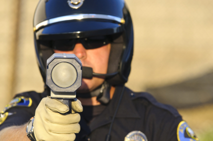 A police officer is holding up his hand to the side.