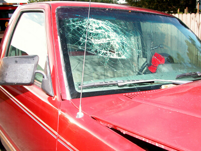 Red pickup truck with shattered windshield and dent