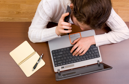 A person sitting at a desk with a laptop and phone.