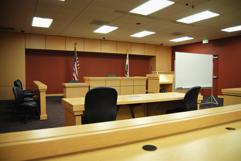 A courtroom with two empty chairs and a desk.