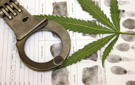 A pair of handcuffs and a marijuana leaf on top of papers.