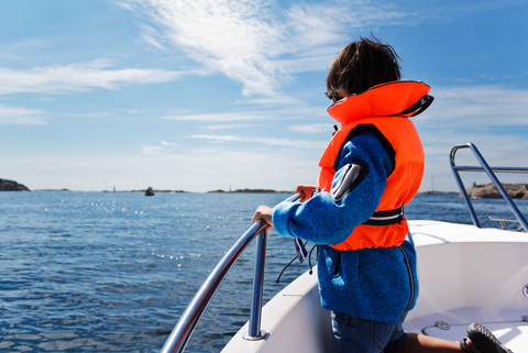 A child in life jacket on boat with ocean view.