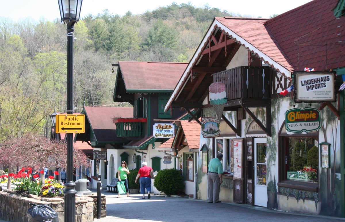 A street with many shops and people walking on the sidewalk.