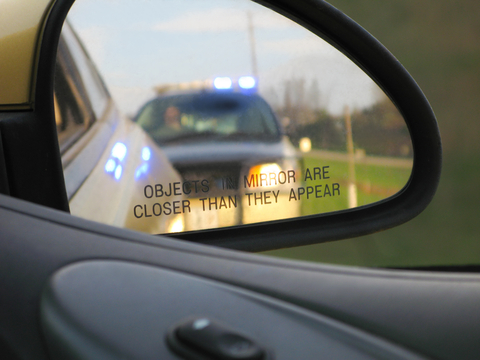 A police car is reflected in the side mirror of a vehicle.